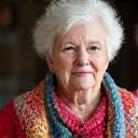 Portrait of Elvira, a senior woman with a warm smile, holding a colorful crochet blanket