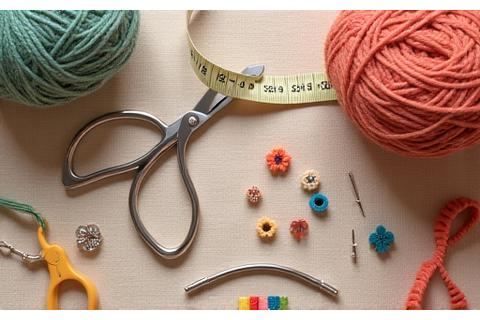 Collection of essential crafting tools: measuring tape, stitch markers, scissors, and darning needles.